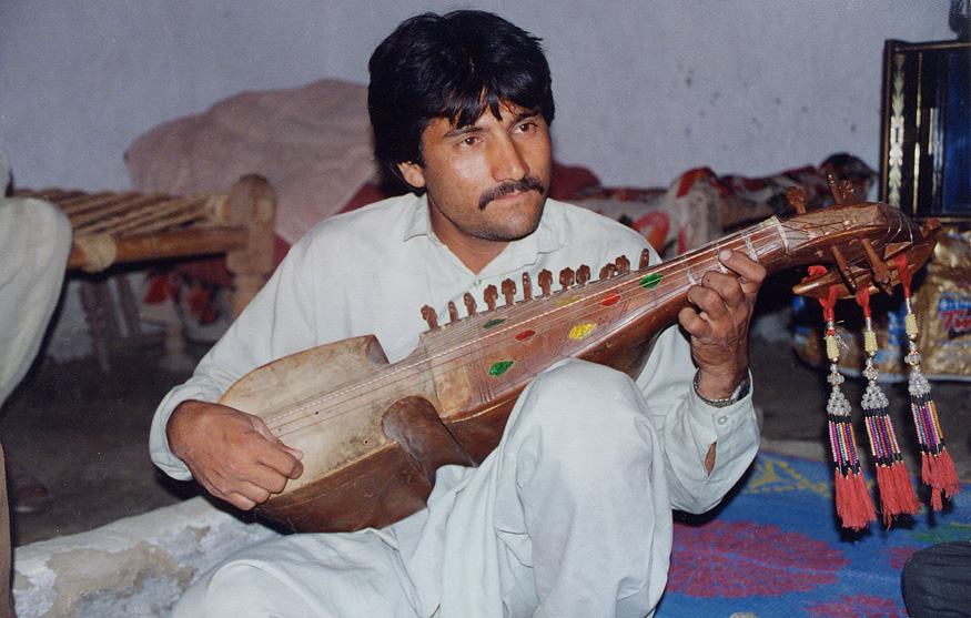 Man Sitting Playing An Instrument / Pakistan / Pushtun - Click Image to Close